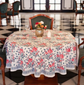 Une nappe Leya, une nappe ronde de 150 cm. Une nappe blanche imprimés fleuris roses et bleus.
