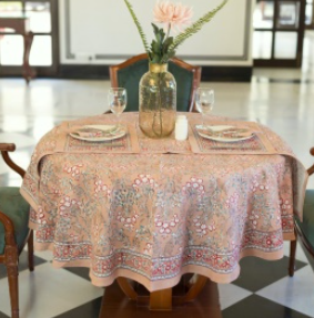Nappe Rani, une nappe ronde sur fond vieux rose aux imprimés fleuris.