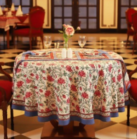 Nappe Sahana, une nappe ronde de 150 cm. Une nappe blanche aux imprimés fleuris rouges, bleus et verts.