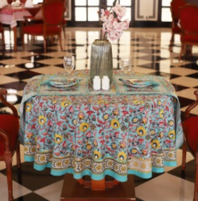 Nappe Siona, une nappe ronde de 150 cm. Une nappe bleue aux imprimés fleuris roses, rouges et jaunes.