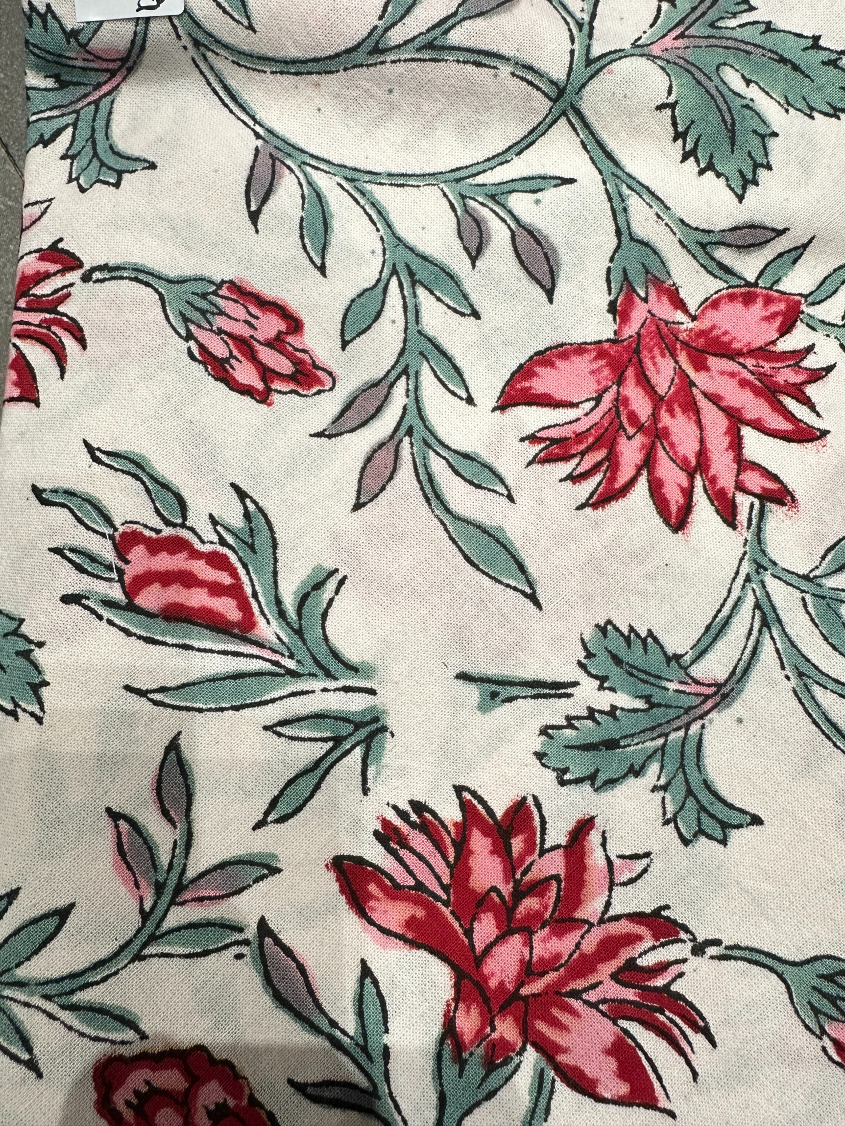 Nappe Sahana, une nappe ronde de 150 cm. Une nappe blanche aux imprimés fleuris rouges, bleus et verts.