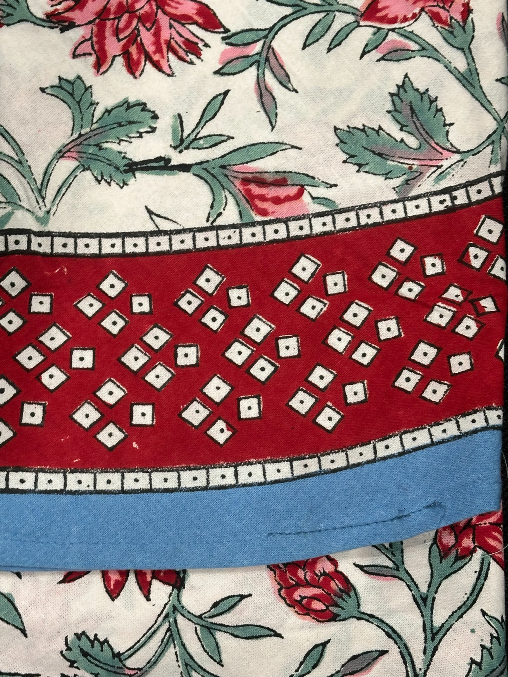 Nappe Sahana, une nappe ronde de 150 cm. Une nappe blanche aux imprimés fleuris rouges, bleus et verts.