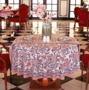 Nappe Kamini, une nappe ronde en 150 cm. Elle est rose, bleu et des touches de violet clair aux imprimés fleuries.