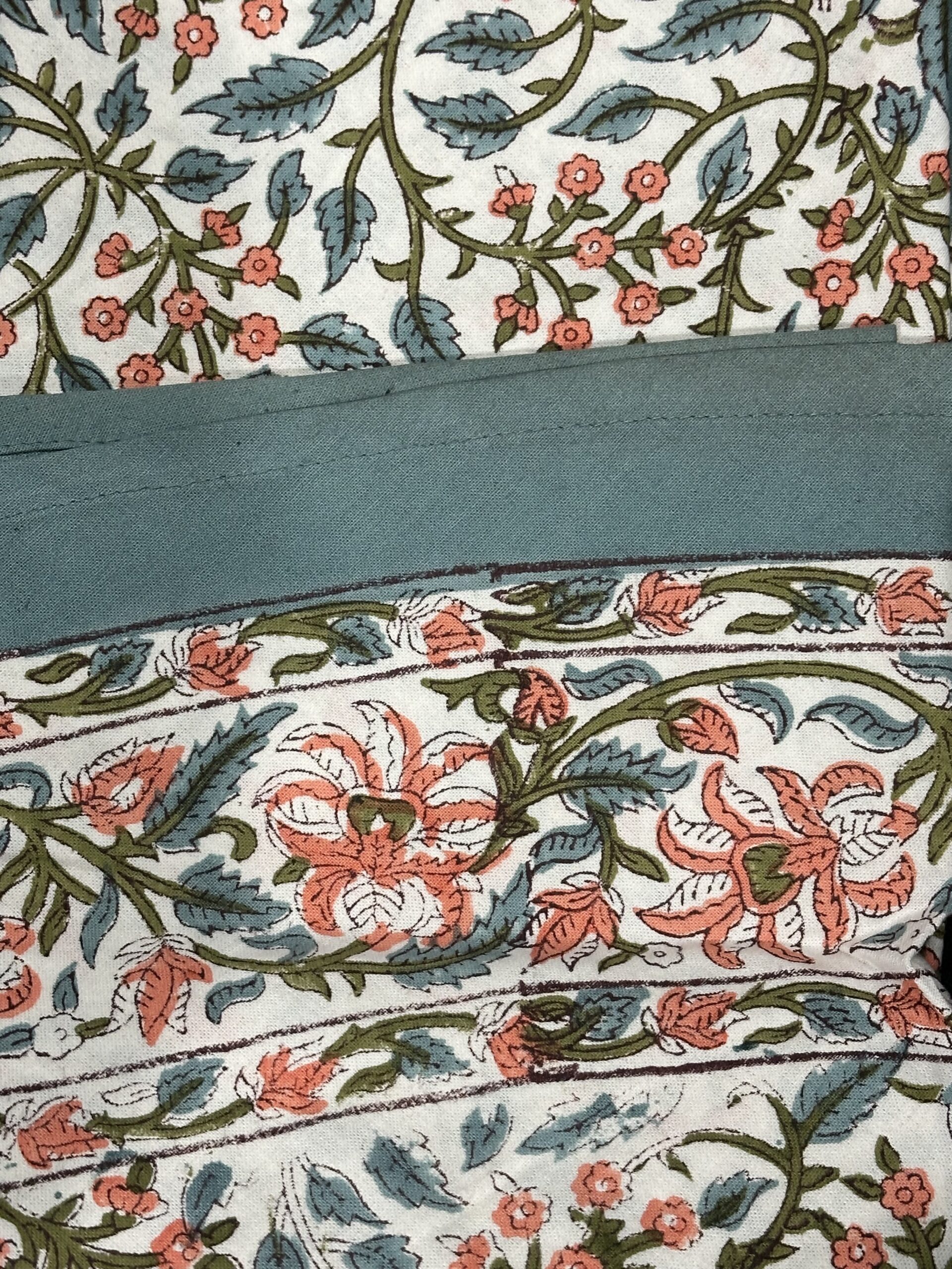 Nappe Kanira, une nappe ronde de 150 cm. Une nappe aux couleurs bleus et oranges et aux imprimés fleuries.