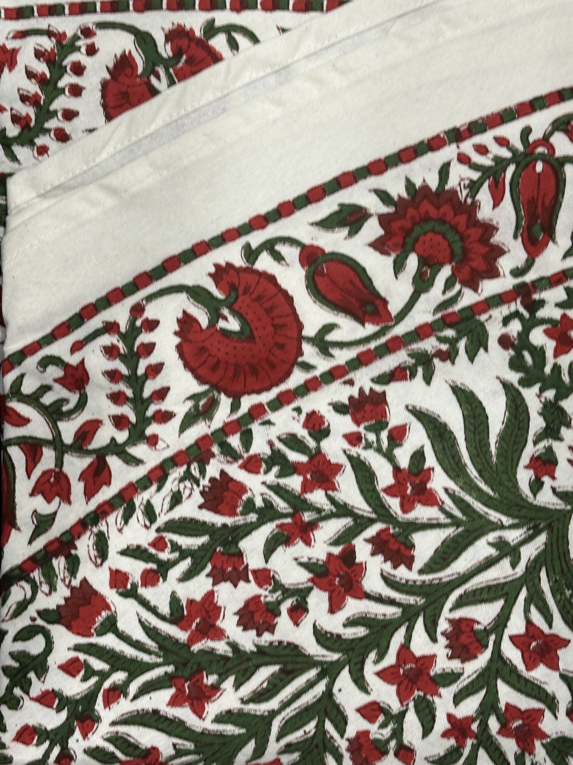 Nappe Ravika, une nappe ronde de 150 cm. Une nappe aux imprimés floraux rouge et vert.