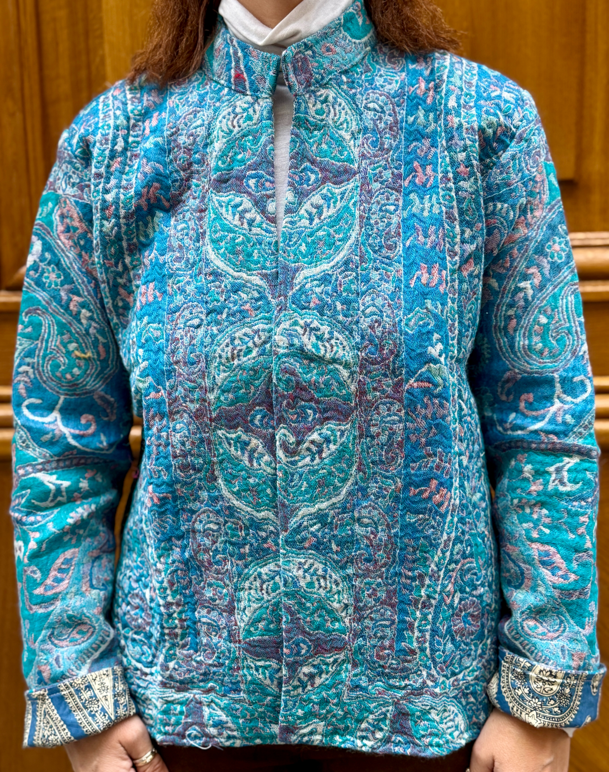 Veste Mehira, une veste en laine avec des nuances de bleus et de roses. Une veste col mao qui arrive en bas du bassin.