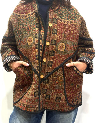 La Veste Kaly, une veste en laine réversible aux imprimés de couleurs foncés bordeaux, verts foncés et noirs et ds bordures noires. Elle comporte deux poches de chaque côtés.