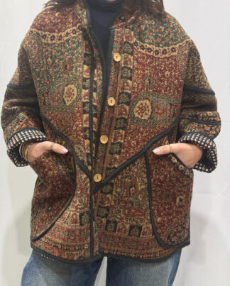 La Veste Kaly, une veste en laine réversible aux imprimés de couleurs foncés bordeaux, verts foncés et noirs et ds bordures noires. Elle comporte deux poches de chaque côtés.