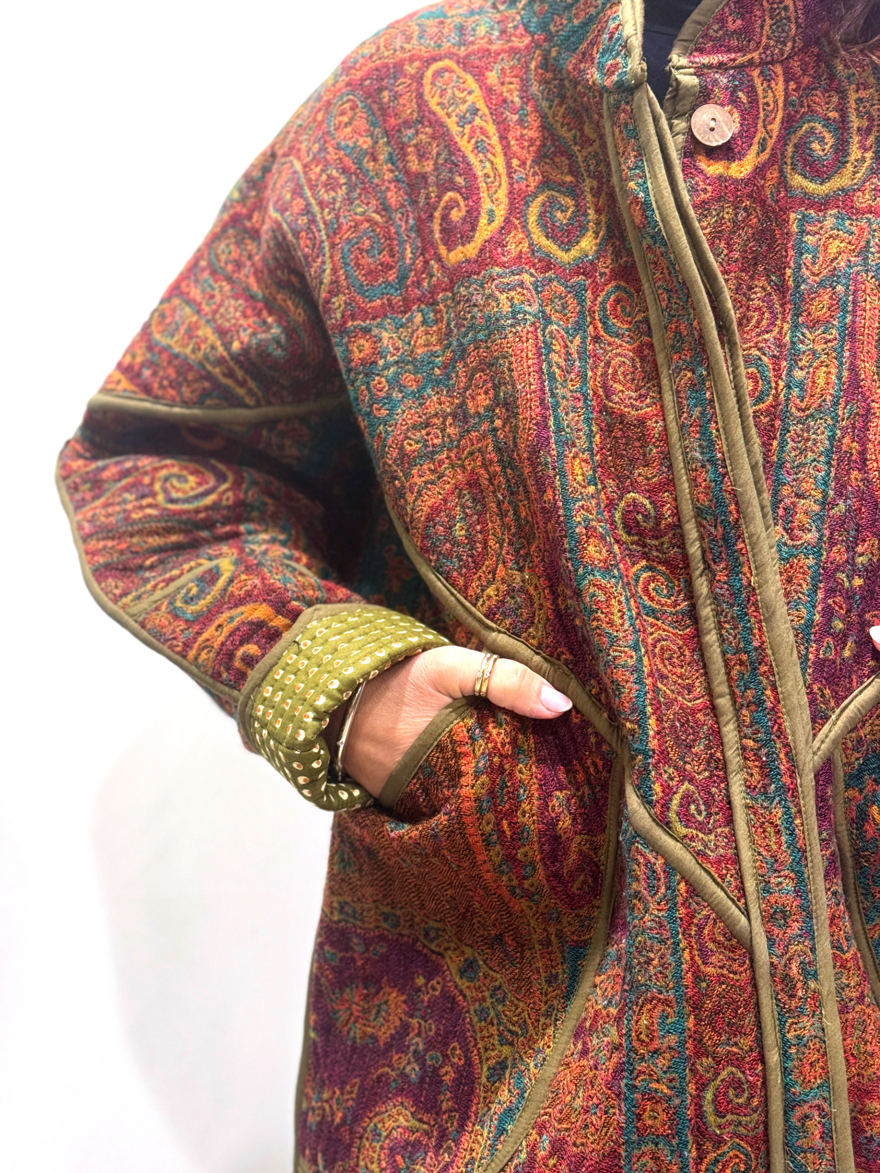 La Veste Iska, une veste en laine réversible aux imprimés de couleurs foncées : kaki, bordeaux, orange et des touches de bleus.