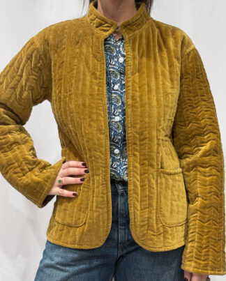 La veste Surya, une veste en velours jaune moutarde. Une veste col mao réversible, en coton imprimé à l'intérieur, jaune et mauve avec des motifs floraux. Une veste parfaite pour la mi saison.
