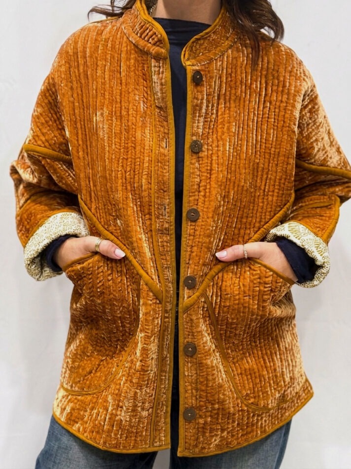 La veste Davia, une veste en velours de soie réversible. Une veste orange clair, et à l'intérieur un imprimé blanc et orange avec des motifs.
