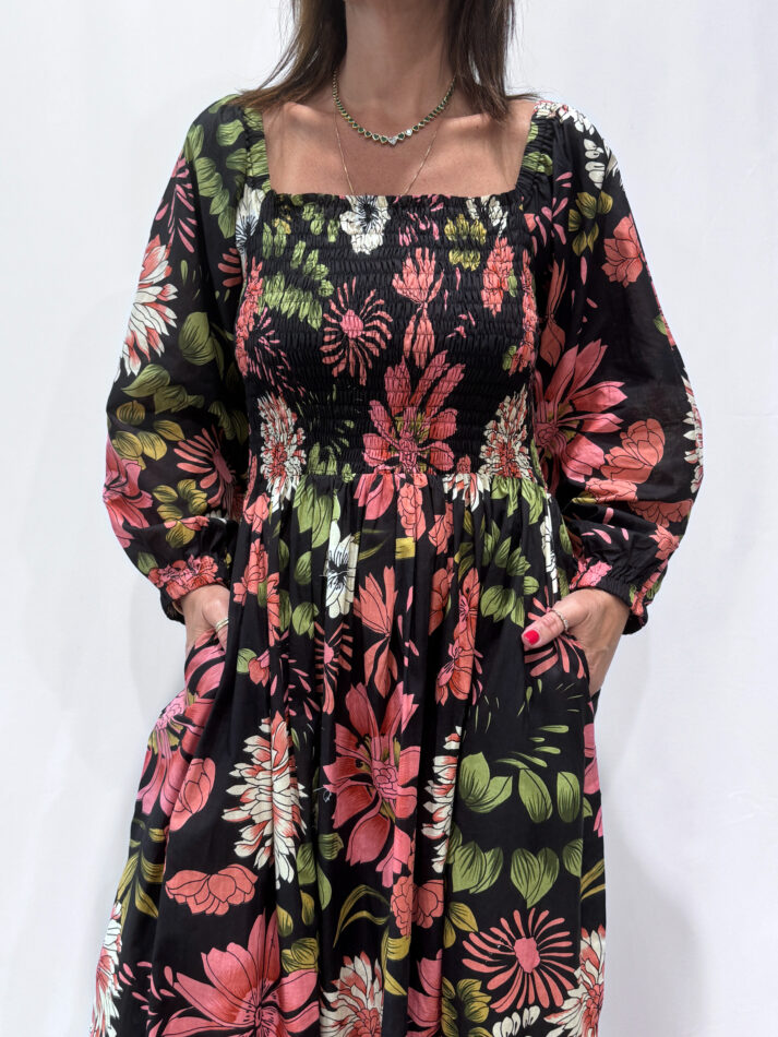 Robe Amira Noire une robe longue smockée. Fluide et 100 % coton. Elle est de couleur noire avec des imprimée fleurit.