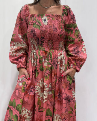 Robe Amira Rose, une robe longue smockée. Fluide et 100 % coton. Elle est rose avec des imprimée fleurit.