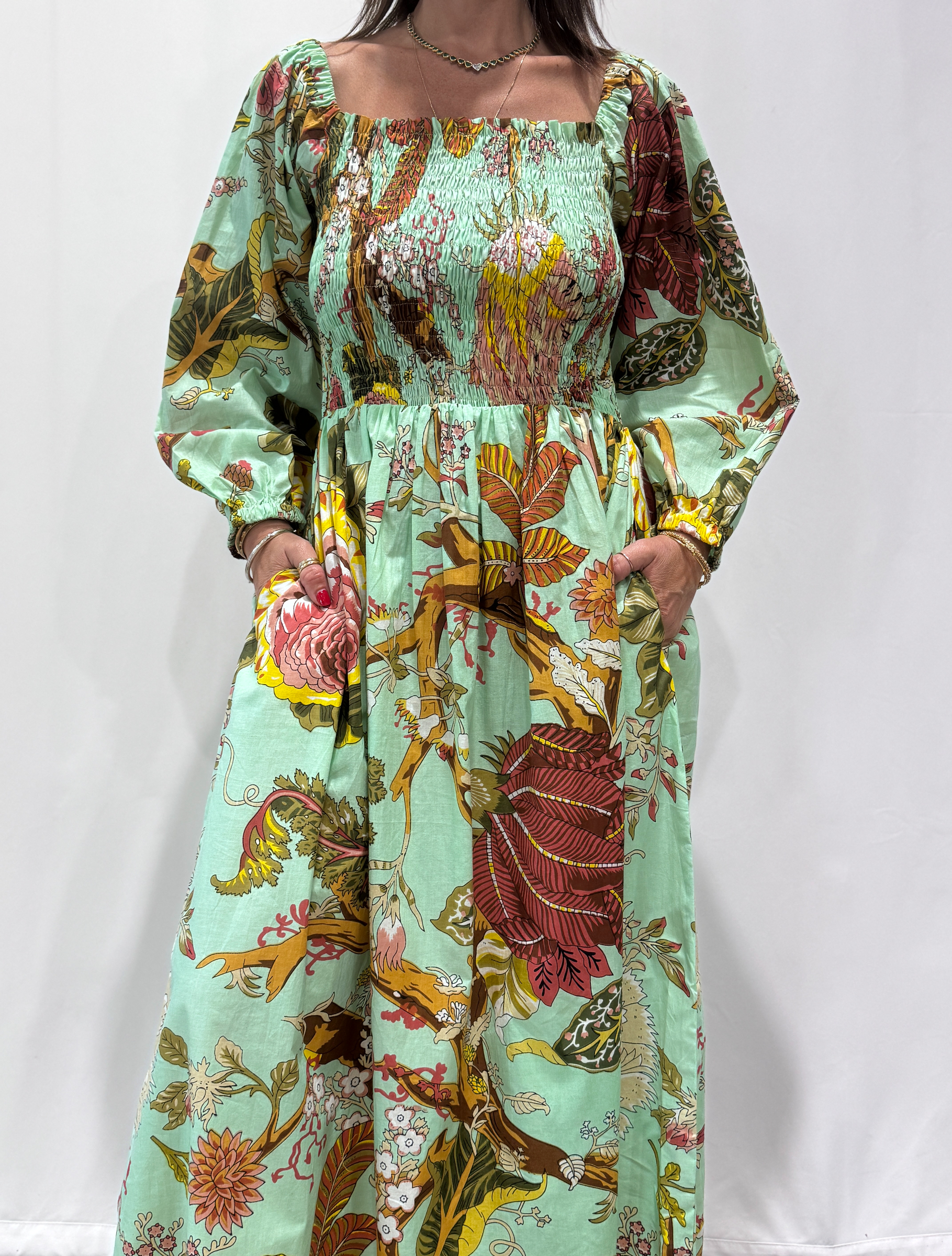 Robe Amira Vert D'eau, une robe longue smockée. Fluide et 100 % coton. Elle est de couleur vert d'eau avec des imprimée fleurit.