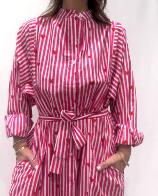 Robe Love Rose, une robe longue rayée rose imprimé de coeurs rouges. Une robe taille unique qui se ceinture à la taille. Des manches longues.