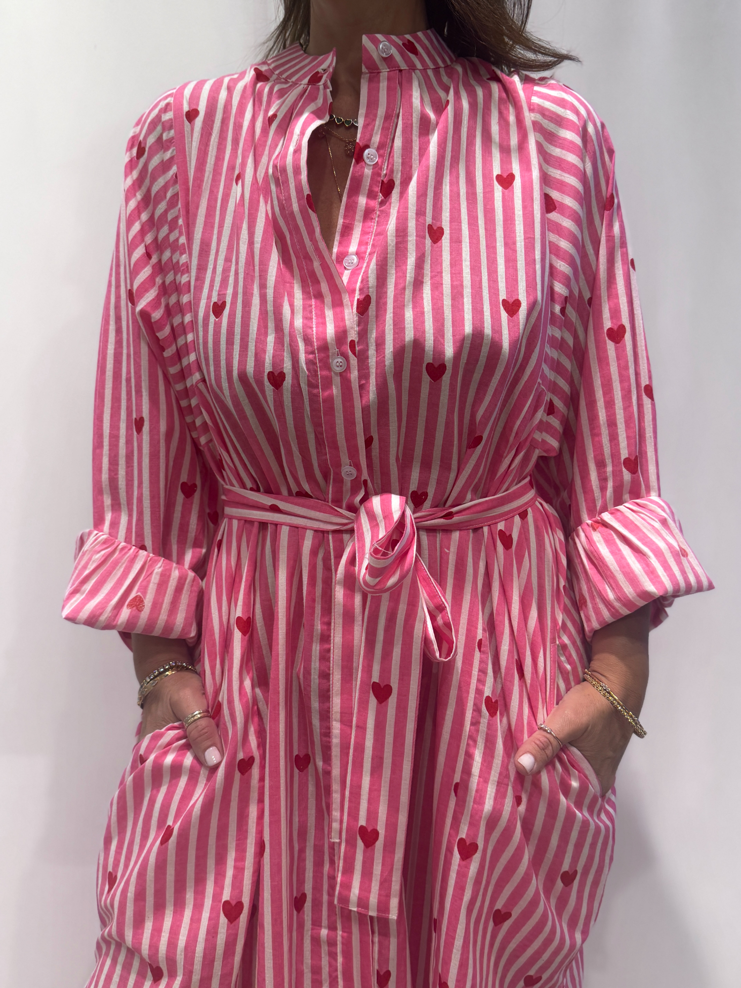 Robe Love Rose Pâle, une robe longue rayée rose pâle imprimé de coeurs rouges. Une robe taille unique qui se ceinture à la taille. Des manches longues.