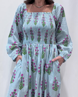 Robe Naya Bleu, une robe longue smockée. Fluide et 100 % coton. Elle est rayée avec des imprimés de fleurs.