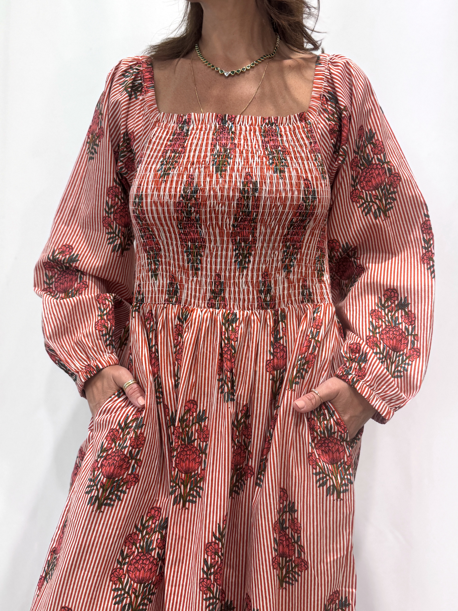 Robe Naya Bordeaux, une robe longue smockée. Fluide et 100 % coton. Elle est rayée avec des imprimés de fleurs.