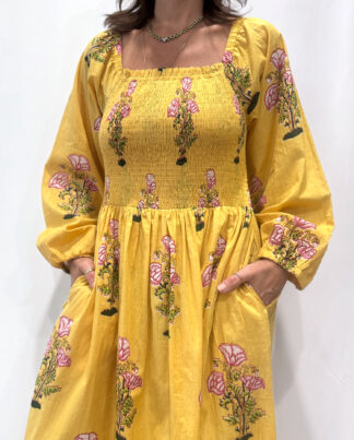 Robe Naya Jaune, une robe longue smockée. Fluide et 100 % coton. Elle est rayée avec des imprimés de fleurs.