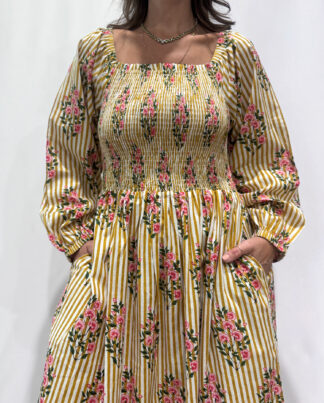 Robe Naya Jaune rayée, une robe longue smockée. Fluide et 100 % coton. Elle est rayée avec des imprimés de fleurs.