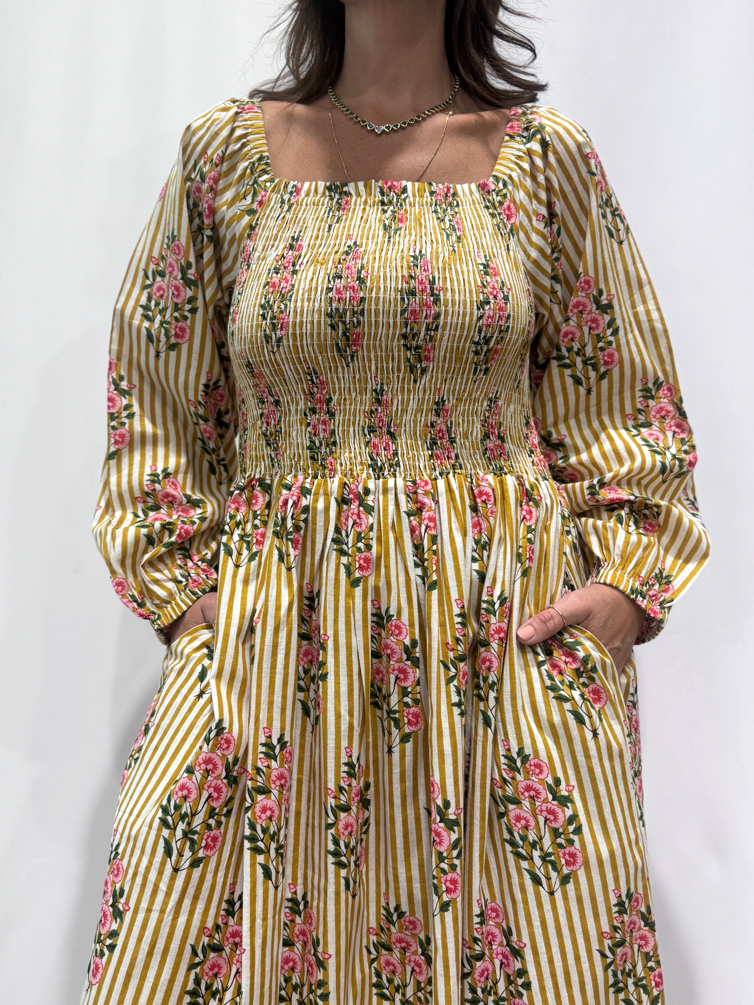 Robe Naya Jaune rayée, une robe longue smockée. Fluide et 100 % coton. Elle est rayée avec des imprimés de fleurs.