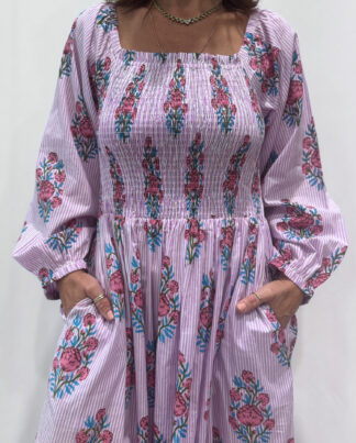 Robe Naya Lila, une robe longue smockée. Fluide et 100 % coton. Elle est rayée avec des imprimés de fleurs.