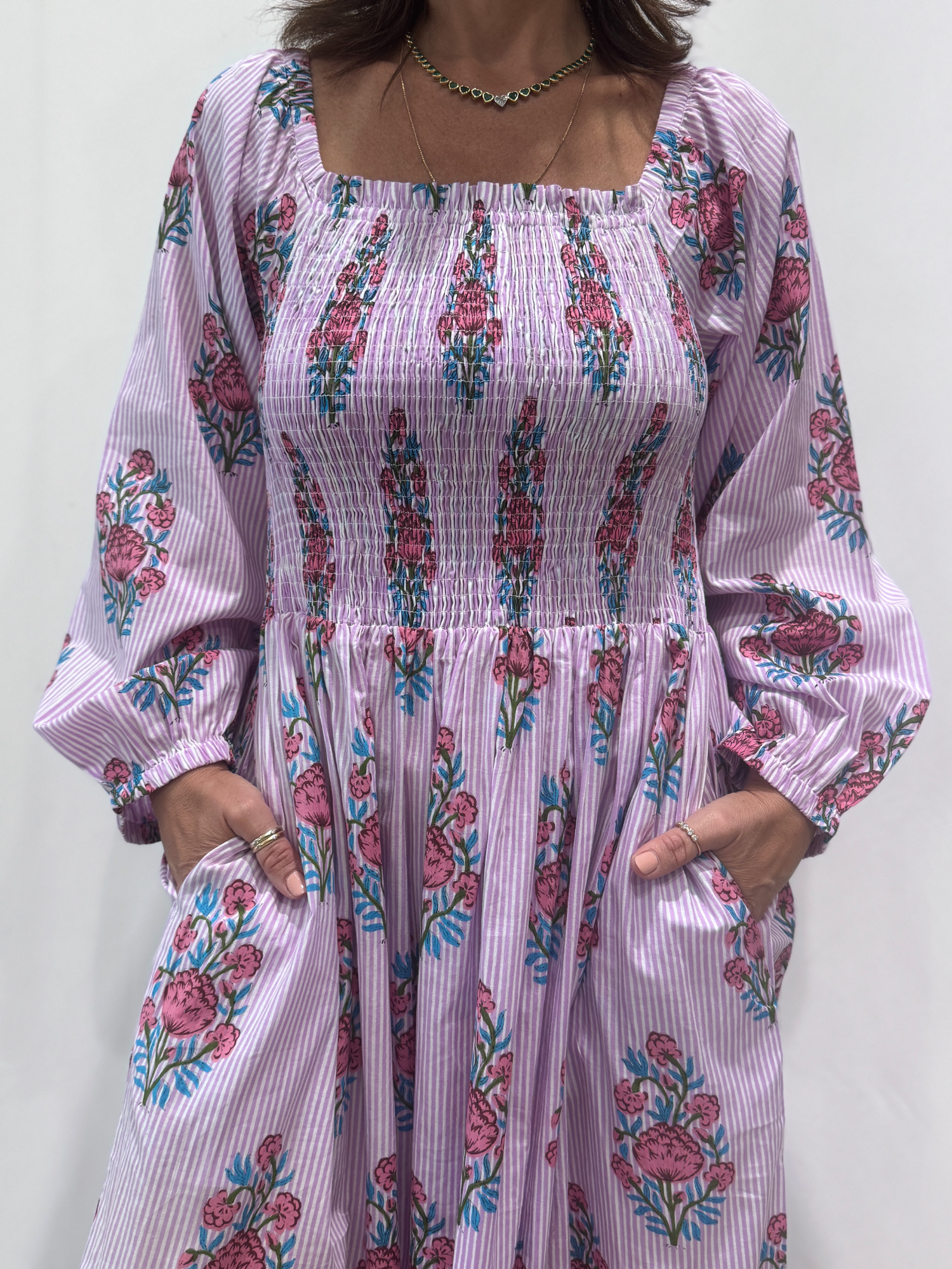 Robe Naya Lila, une robe longue smockée. Fluide et 100 % coton. Elle est rayée avec des imprimés de fleurs.