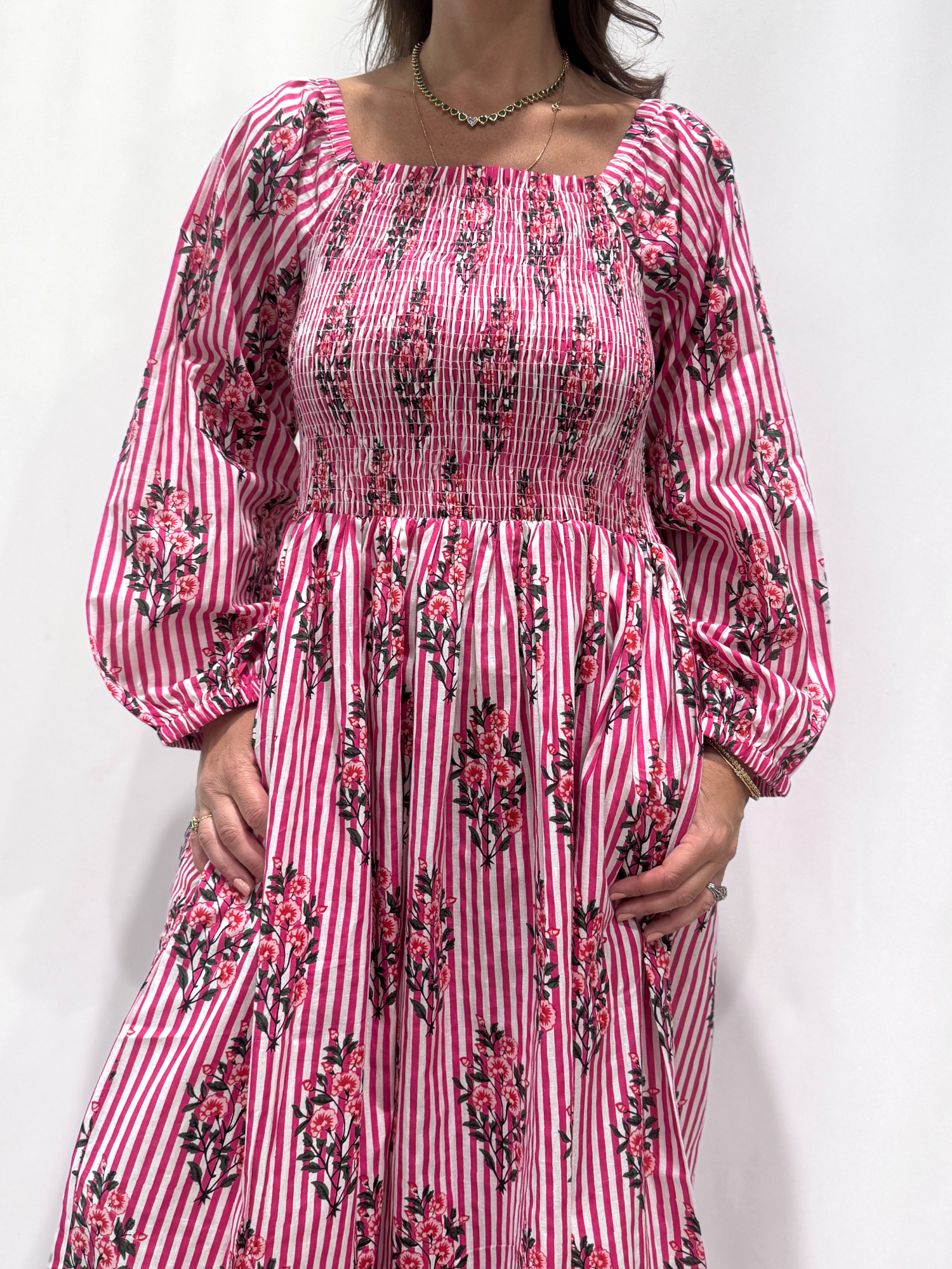 Robe Naya Rose Rayée, une robe longue smockée. Fluide et 100 % coton. Elle est rayée avec des imprimés de fleurs.