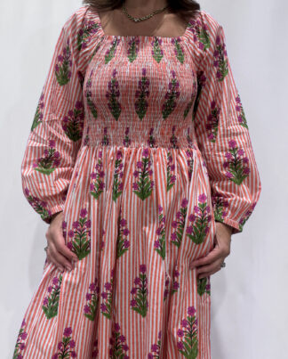 Robe Naya Saumon fleurs mauves, une robe longue smockée. Fluide et 100 % coton. Elle est rayée avec des imprimés de fleurs.