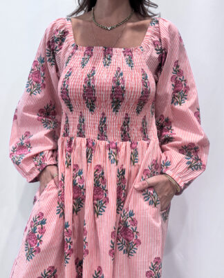 Robe Naya Saumon fleurs roses, une robe longue smockée. Fluide et 100 % coton. Elle est rayée avec des imprimés de fleurs.