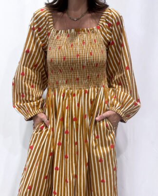 La robe Pyaar Jaune, une robe longue manches longues, smockée à rayures et imprimés de coeurs. Une robe tendance pour cet été.