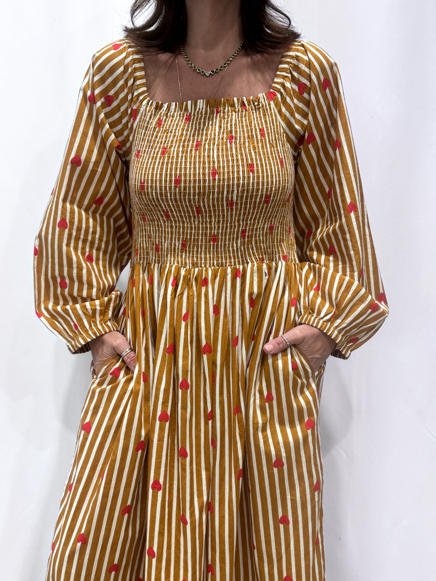 La robe Pyaar Jaune, une robe longue manches longues, smockée à rayures et imprimés de coeurs. Une robe tendance pour cet été.