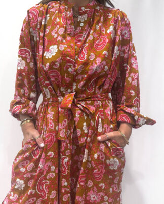 Robe Upama Terracotta, une robe longue avec des imprimés floraux. Une robe taille unique qui se ceinture à la taille. Des manches longues.