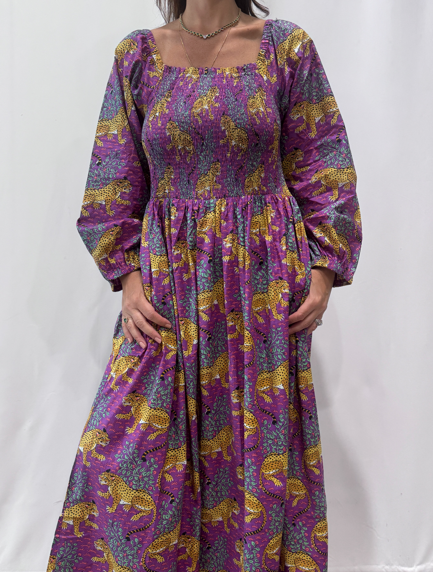 Robe Léora Violette, une robe longue smockée. Fluide et 100 % coton. Elle est de couleur violette avec des imprimés de léopard.