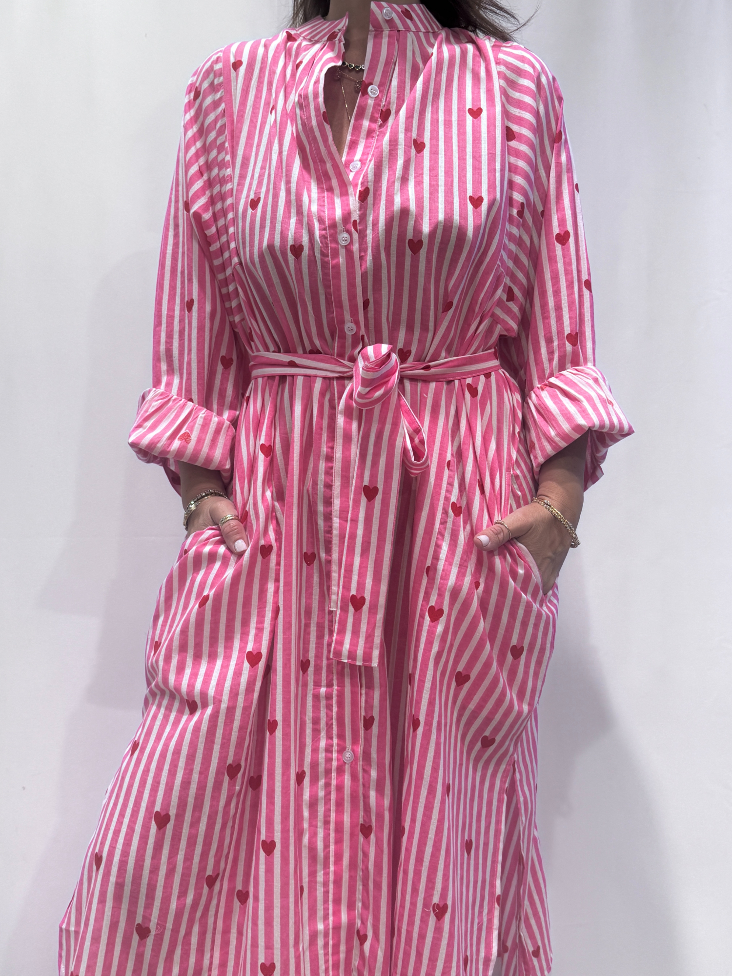 Robe Love Rose Pâle, une robe longue rayée rose pâle imprimé de coeurs rouges. Une robe taille unique qui se ceinture à la taille. Des manches longues.