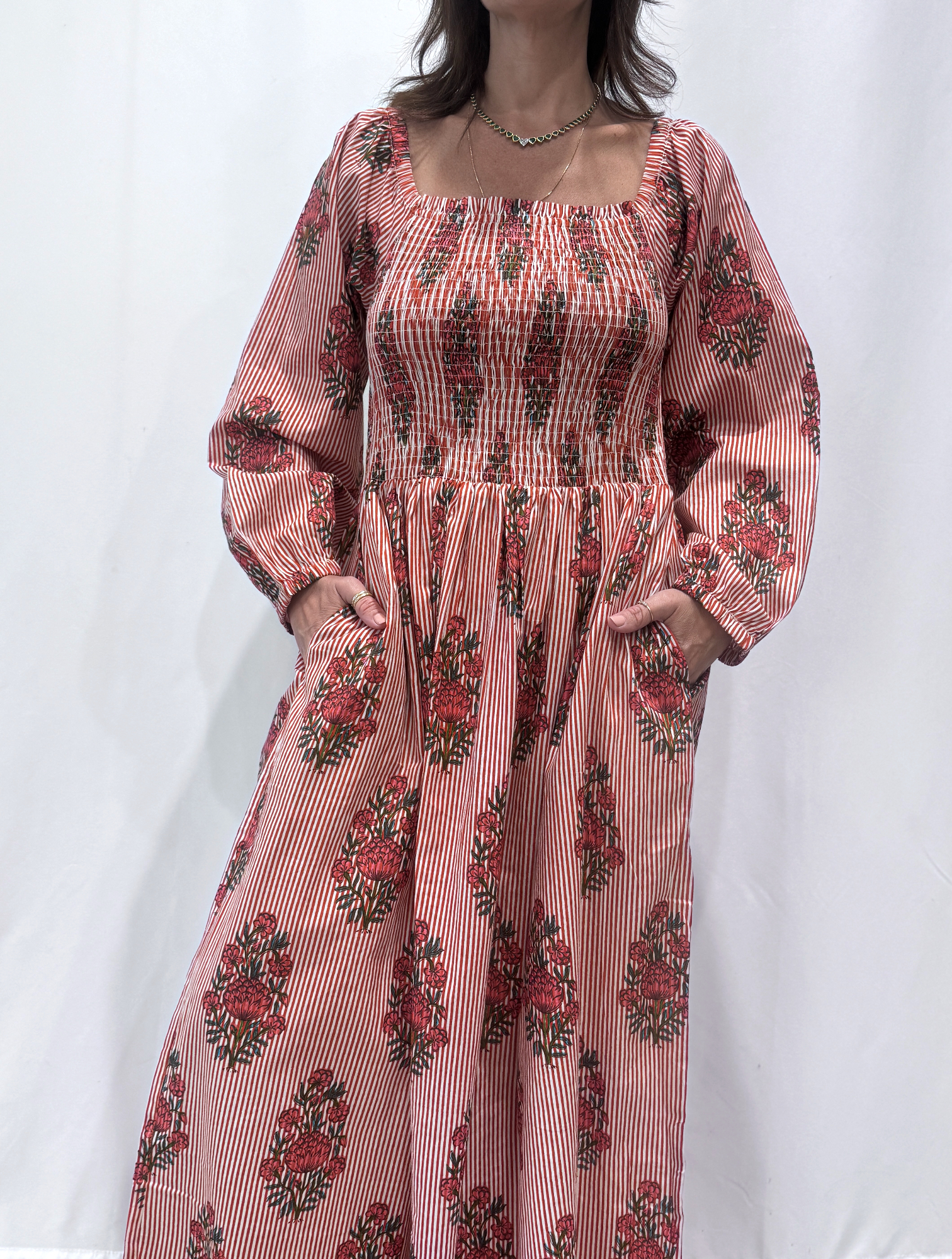 Robe Naya Bordeaux, une robe longue smockée. Fluide et 100 % coton. Elle est rayée avec des imprimés de fleurs.