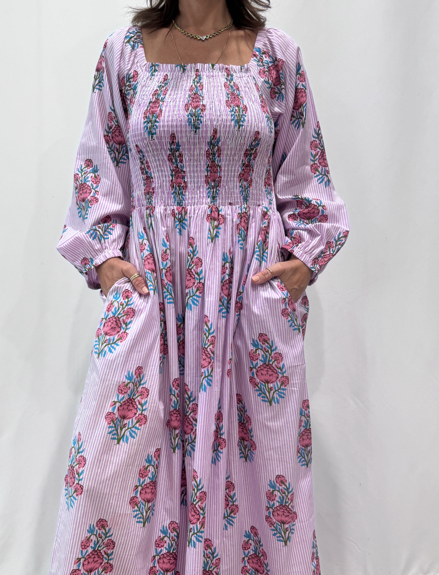 Robe Naya Lila, une robe longue smockée. Fluide et 100 % coton. Elle est rayée avec des imprimés de fleurs.