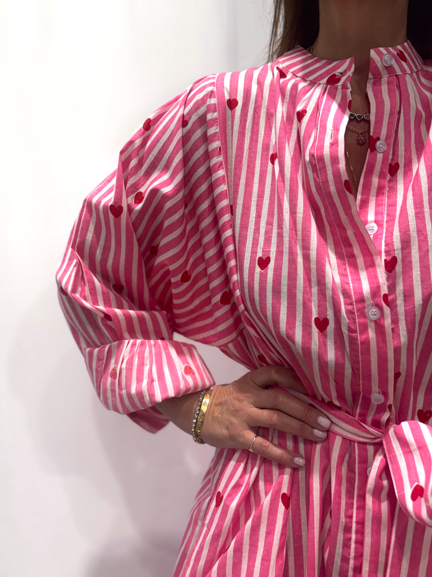 Robe Love Rose Pâle, une robe longue rayée rose pâle imprimé de coeurs rouges. Une robe taille unique qui se ceinture à la taille. Des manches longues.
