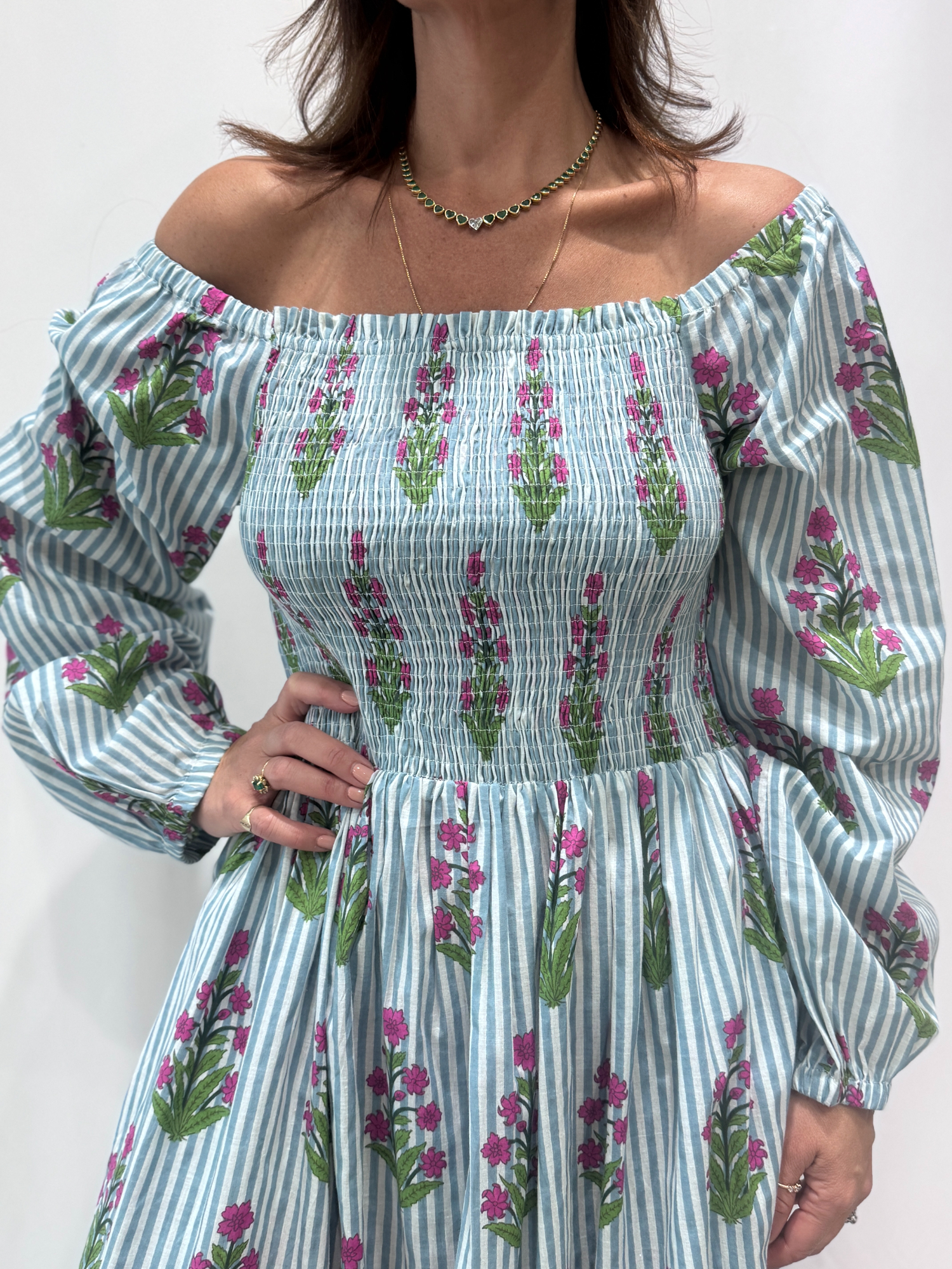 Robe Naya Bleu, une robe longue smockée. Fluide et 100 % coton. Elle est rayée avec des imprimés de fleurs.