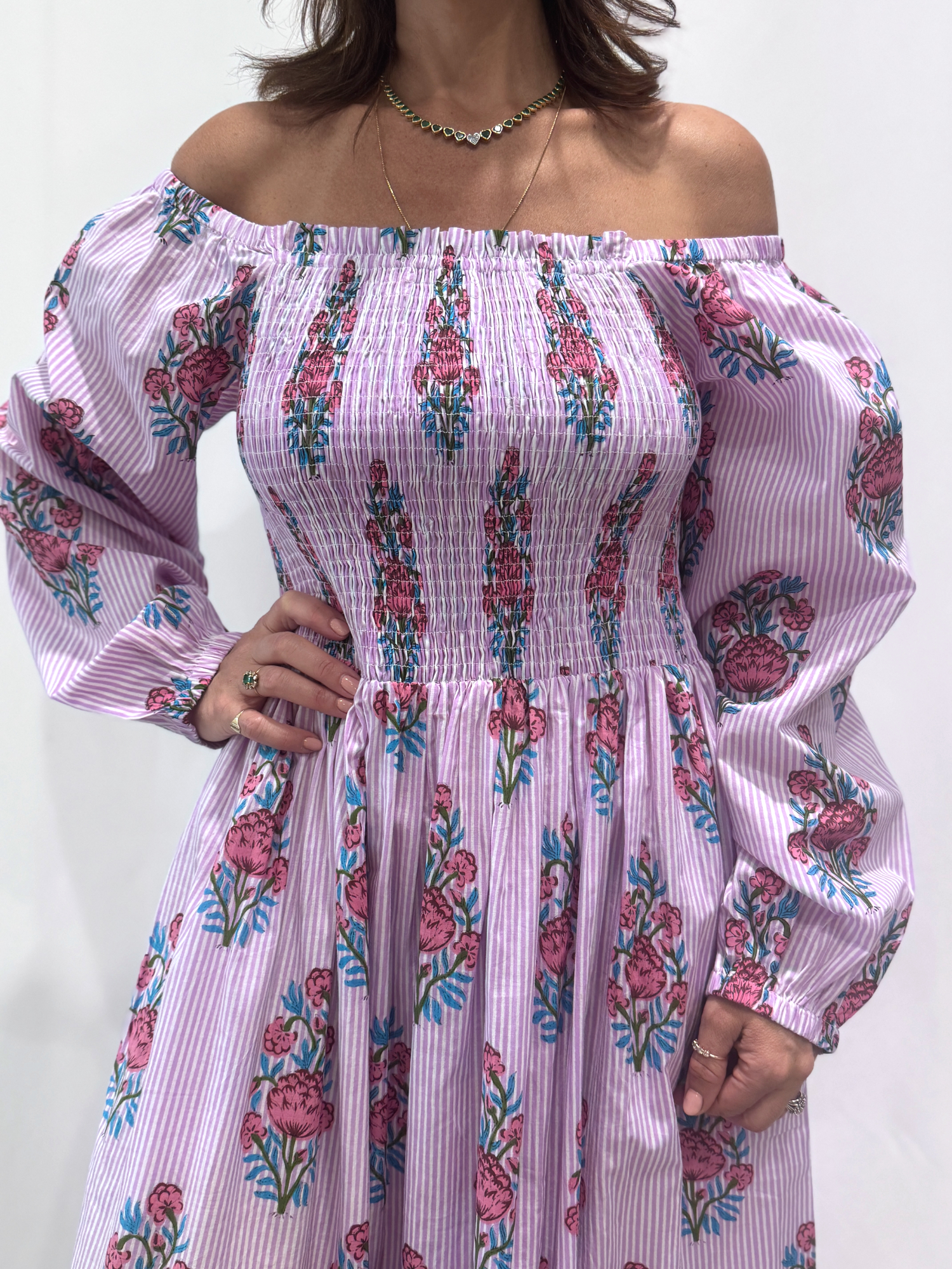 Robe Naya Lila, une robe longue smockée. Fluide et 100 % coton. Elle est rayée avec des imprimés de fleurs.