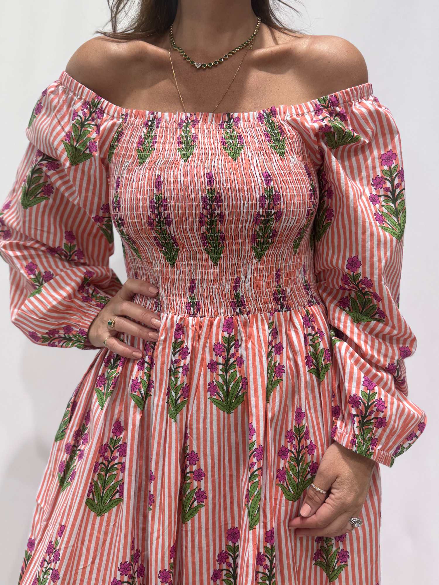 Robe Naya Saumon fleurs mauves, une robe longue smockée. Fluide et 100 % coton. Elle est rayée avec des imprimés de fleurs.
