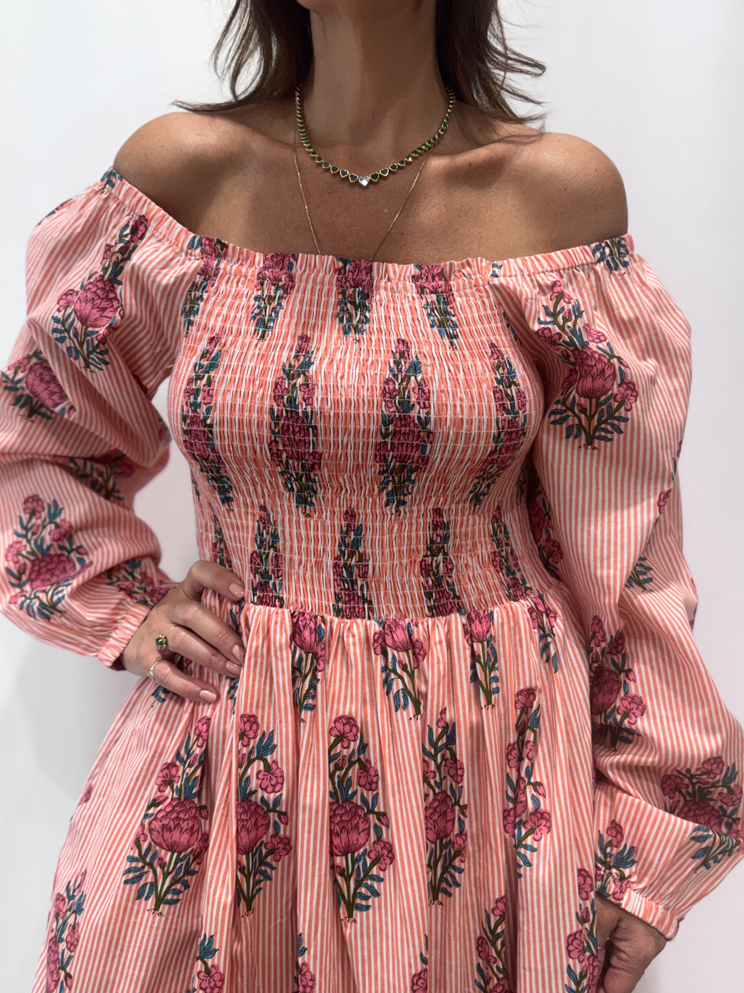 Robe Naya Saumon fleurs roses, une robe longue smockée. Fluide et 100 % coton. Elle est rayée avec des imprimés de fleurs.