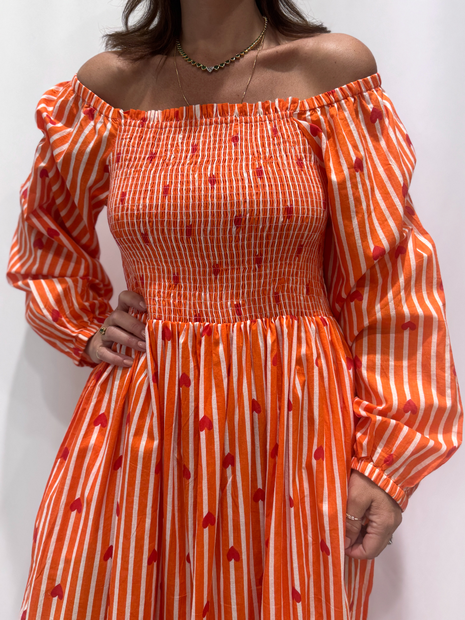 La robe Pyaar Orange, une robe longue manches longues, smockée à rayures et imprimés de coeurs. Une robe tendance pour cet été.