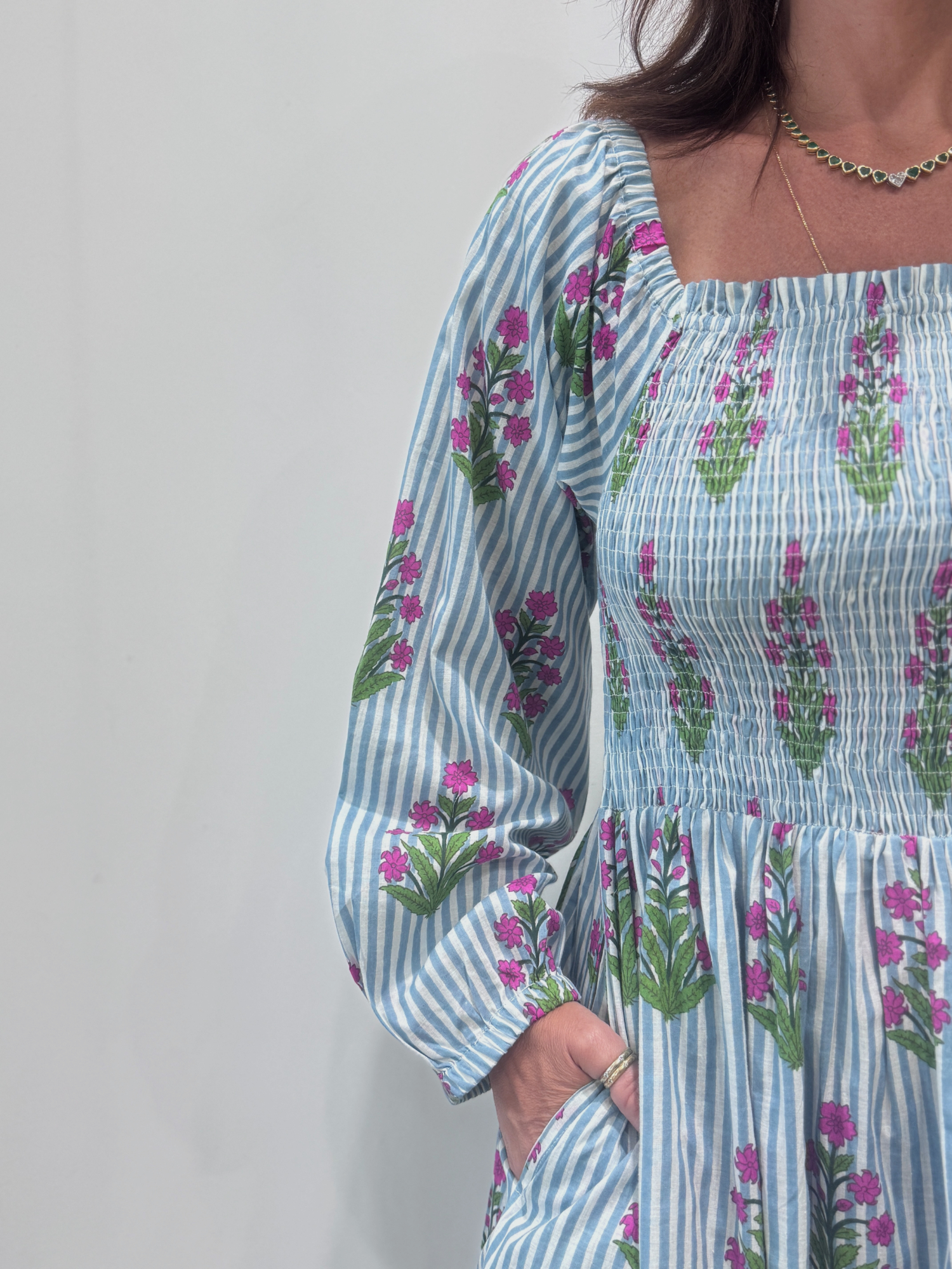 Robe Naya Bleu, une robe longue smockée. Fluide et 100 % coton. Elle est rayée avec des imprimés de fleurs.