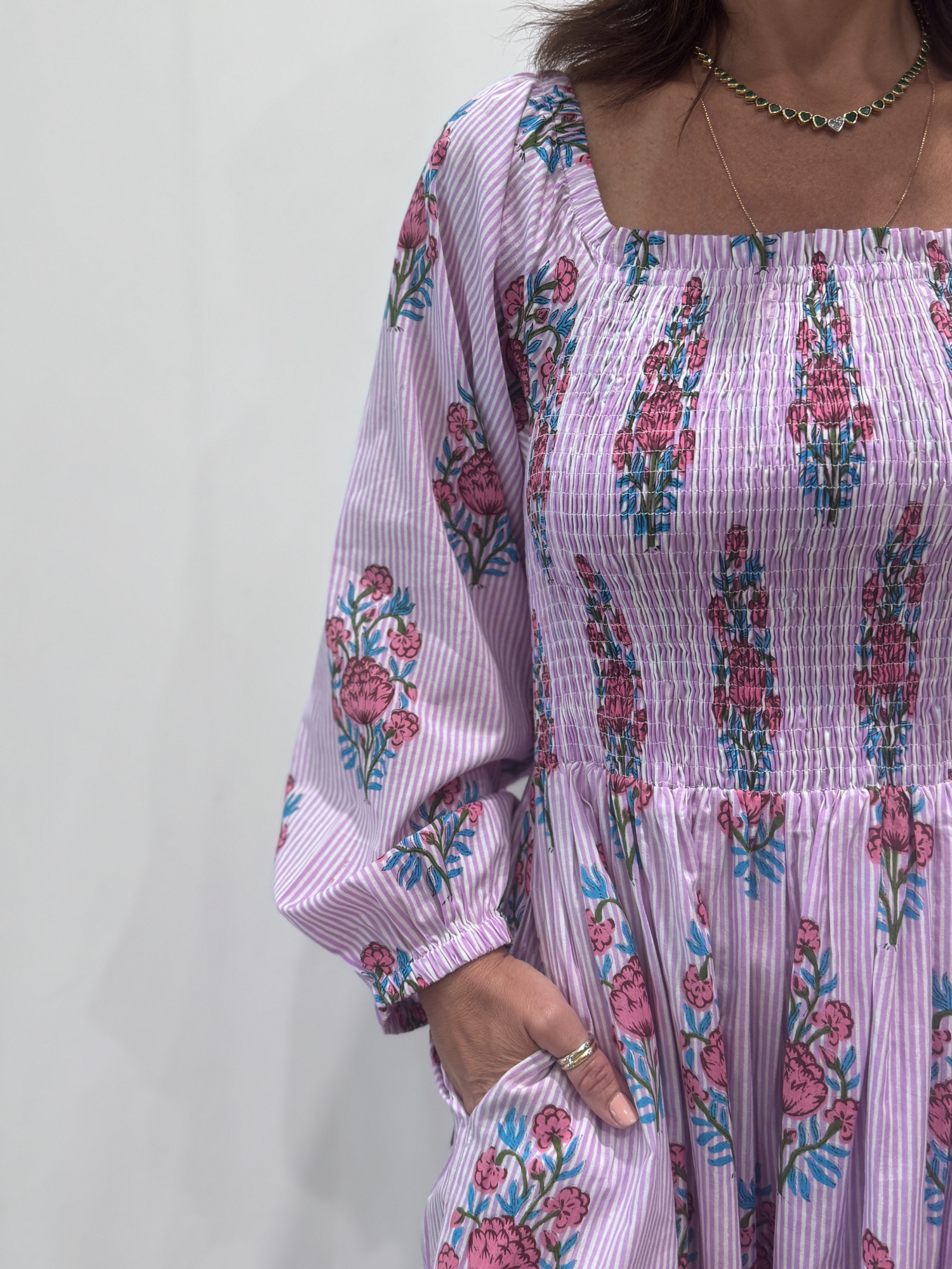 Robe Naya Lila, une robe longue smockée. Fluide et 100 % coton. Elle est rayée avec des imprimés de fleurs.
