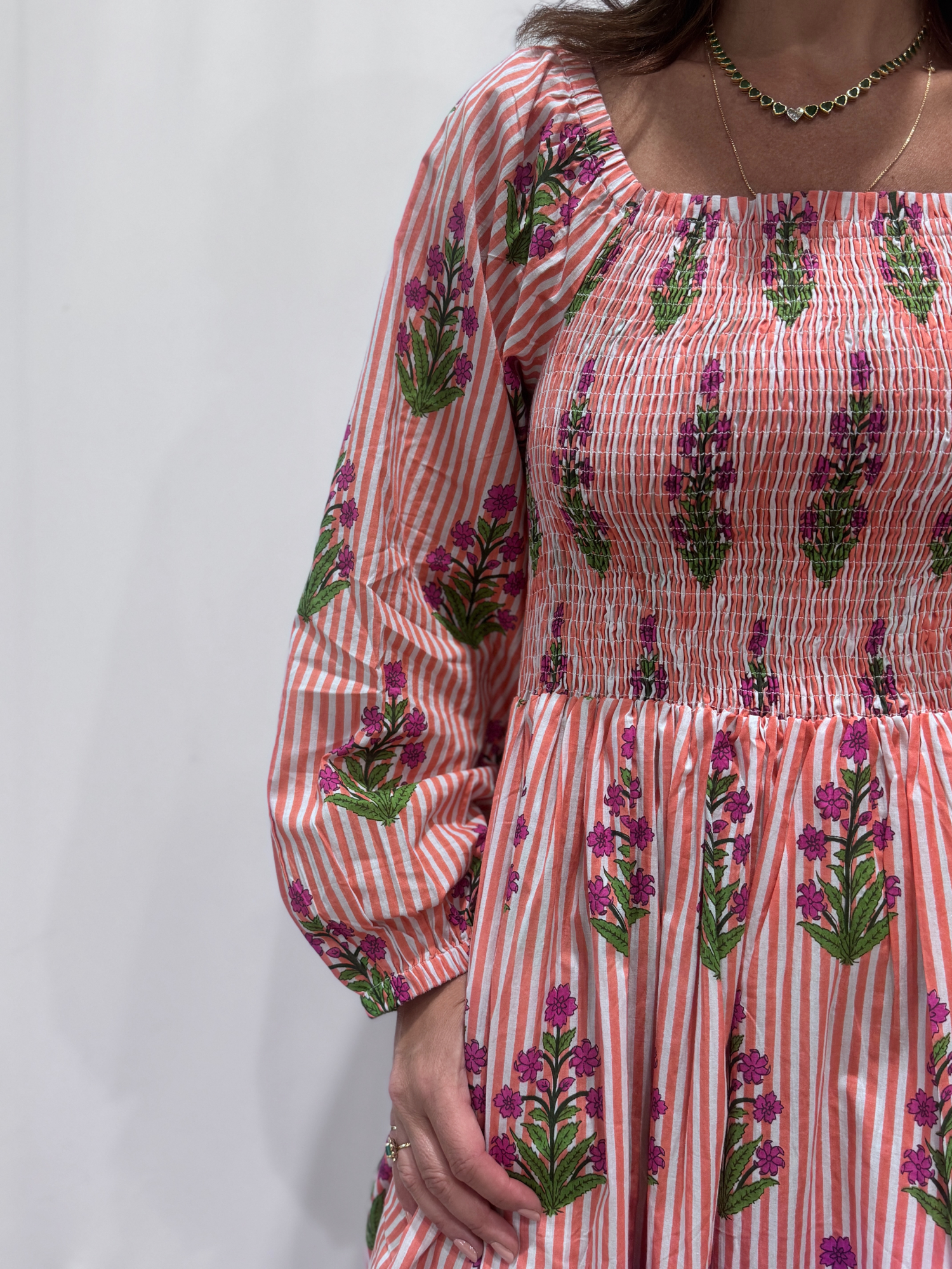 Robe Naya Saumon fleurs mauves, une robe longue smockée. Fluide et 100 % coton. Elle est rayée avec des imprimés de fleurs.