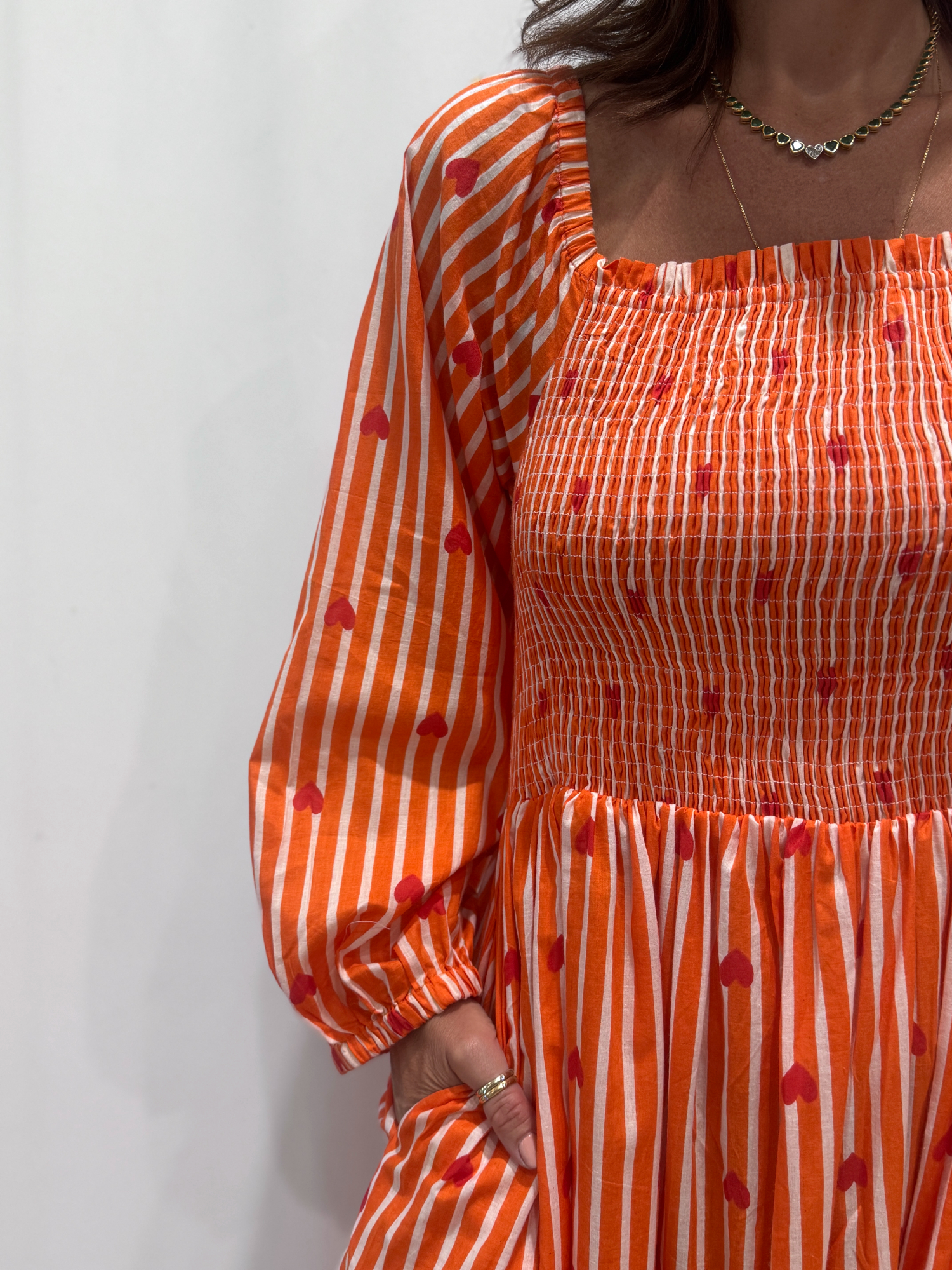 La robe Pyaar Orange, une robe longue manches longues, smockée à rayures et imprimés de coeurs. Une robe tendance pour cet été.