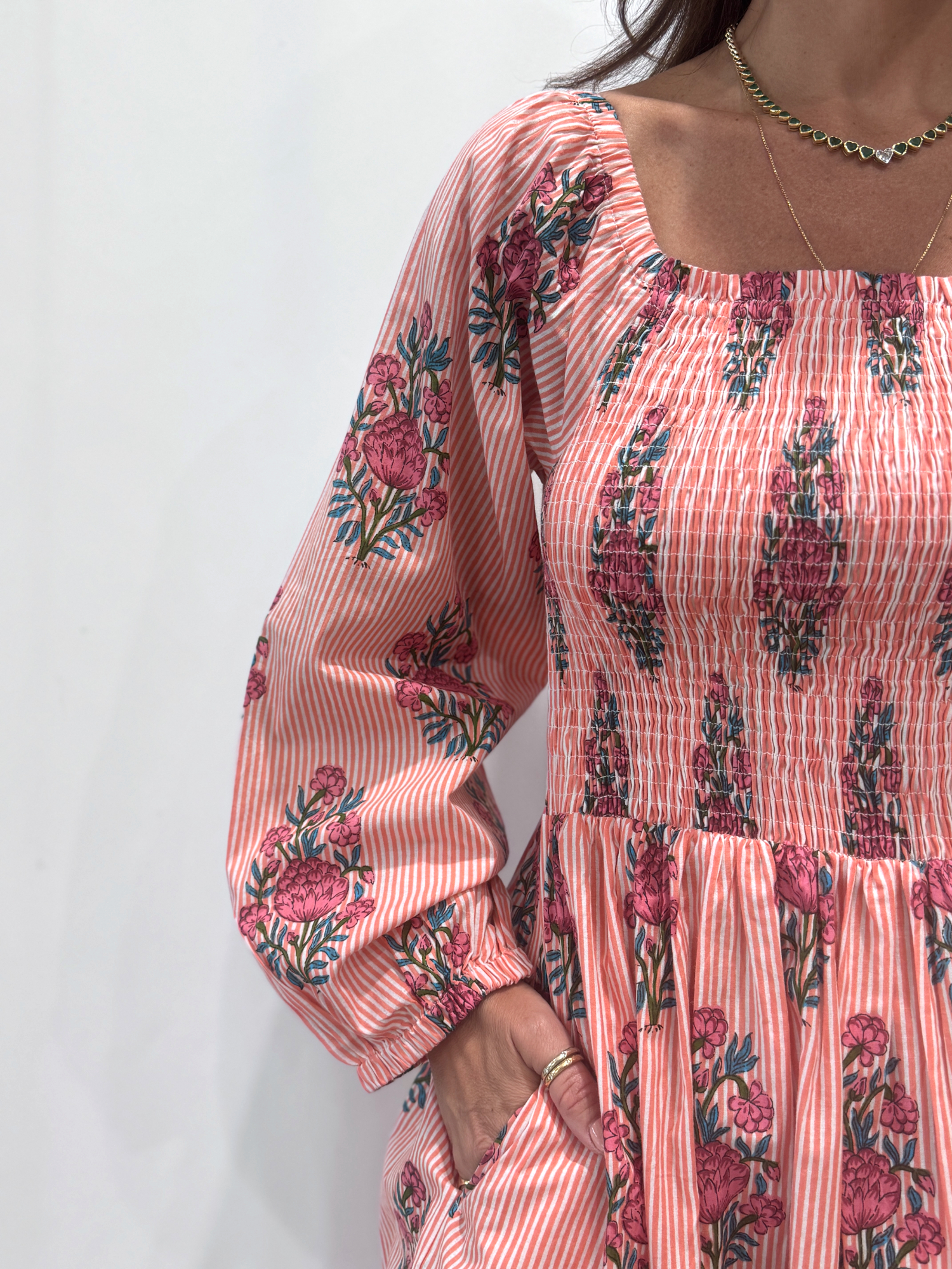 Robe Naya Saumon fleurs roses, une robe longue smockée. Fluide et 100 % coton. Elle est rayée avec des imprimés de fleurs.