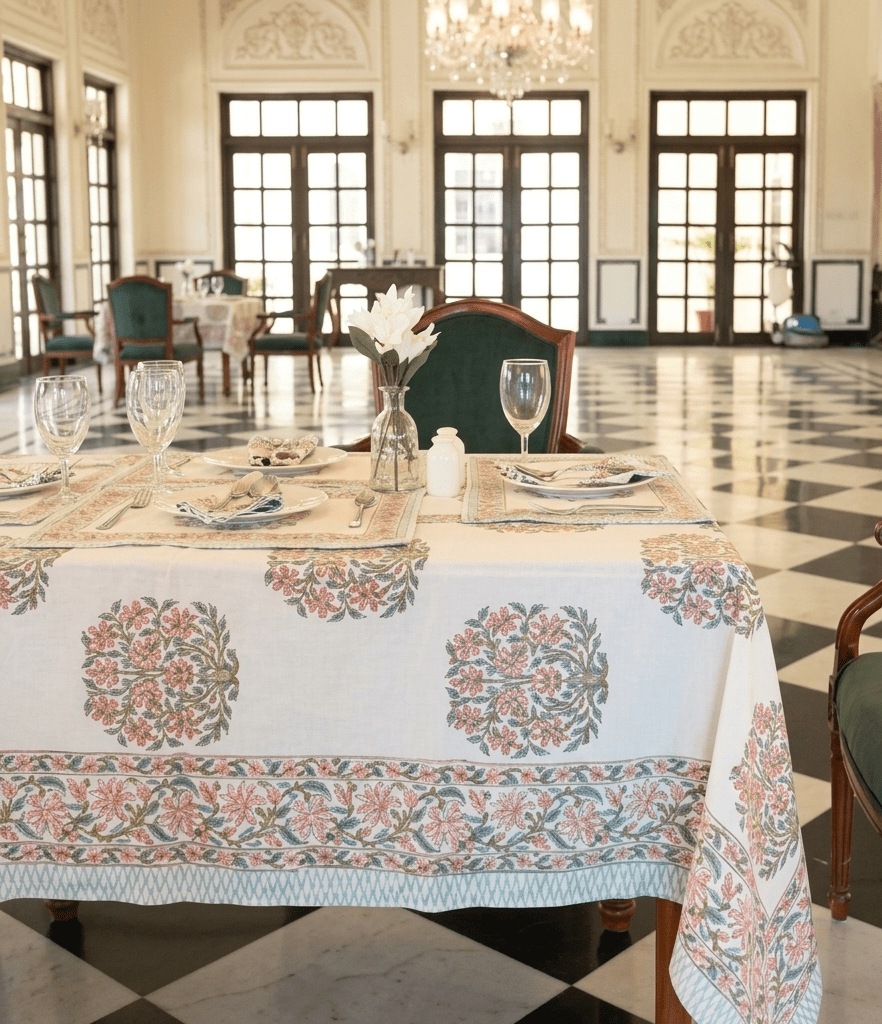La nappe Juhi, une nappe sur fonc blanc avec des imprimés floraux bleus et oranges.