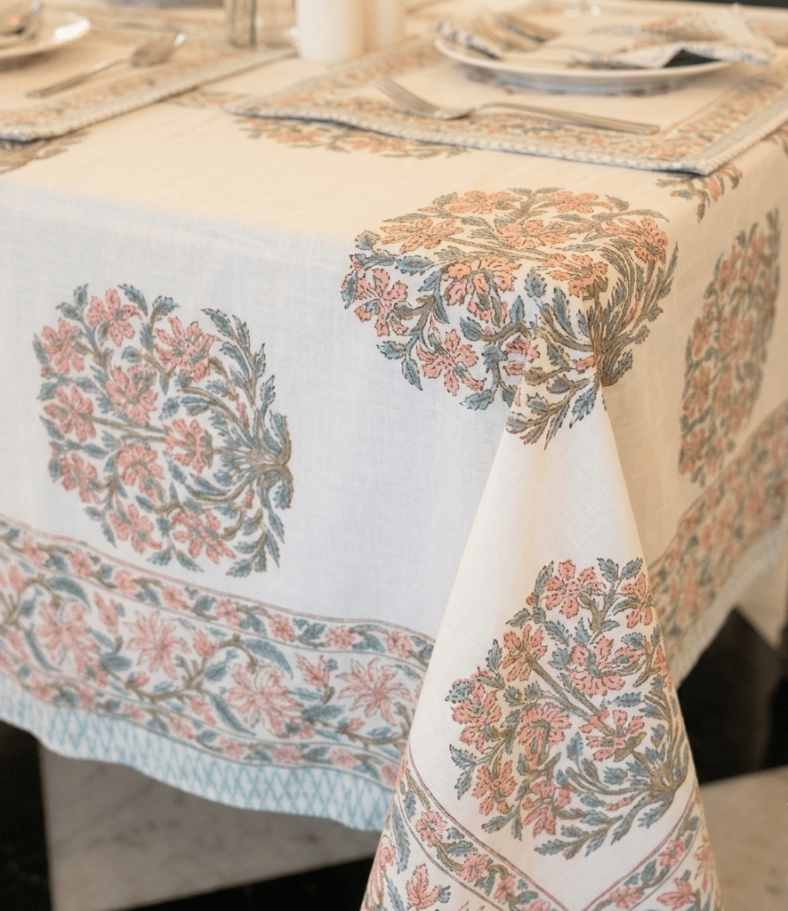 La nappe Juhi, une nappe sur fonc blanc avec des imprimés floraux bleus et oranges.
